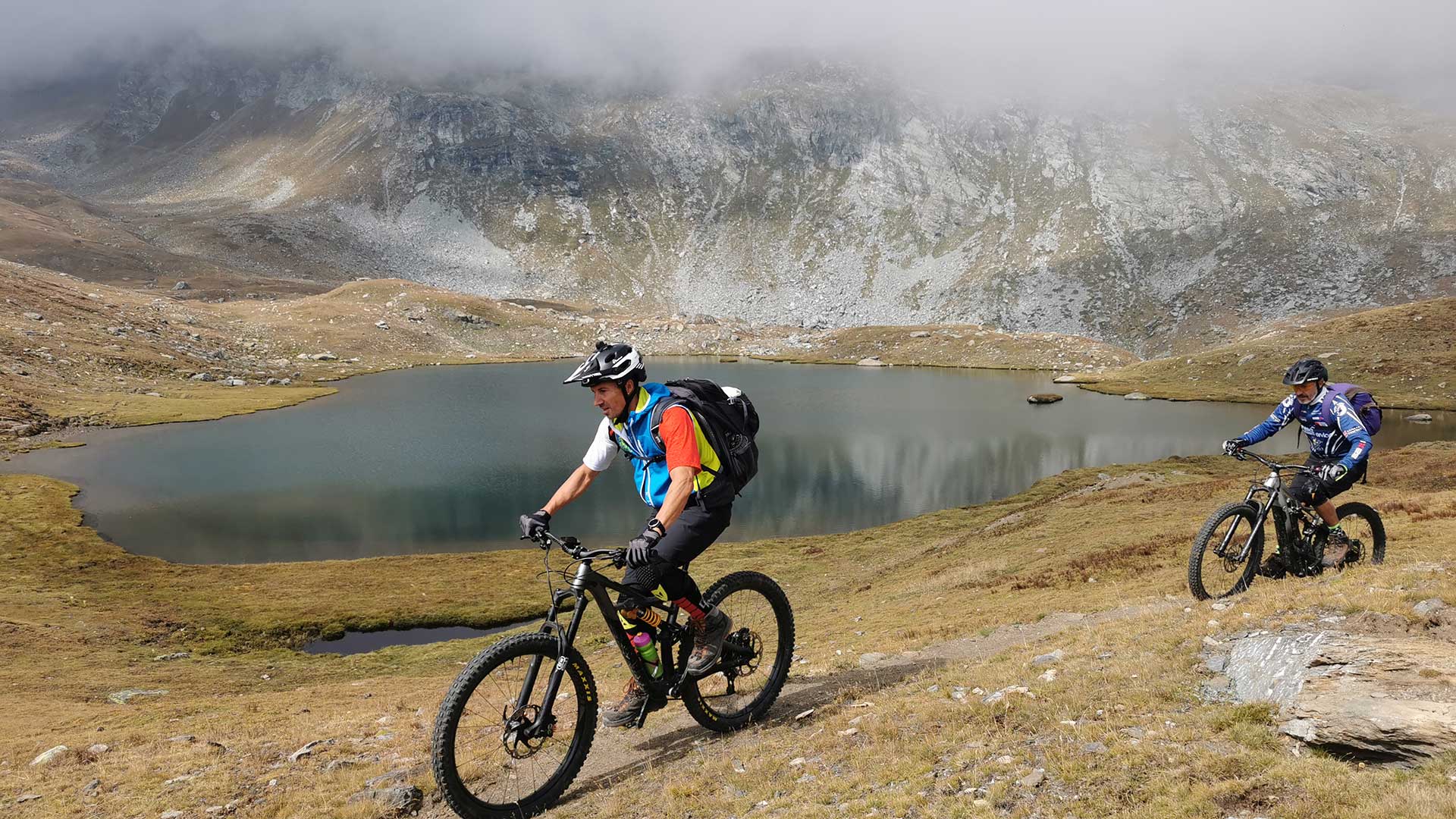 Due biker in mountain bike lungo un lago d'alta quota nel Parco Nazionale del Gran Paradiso